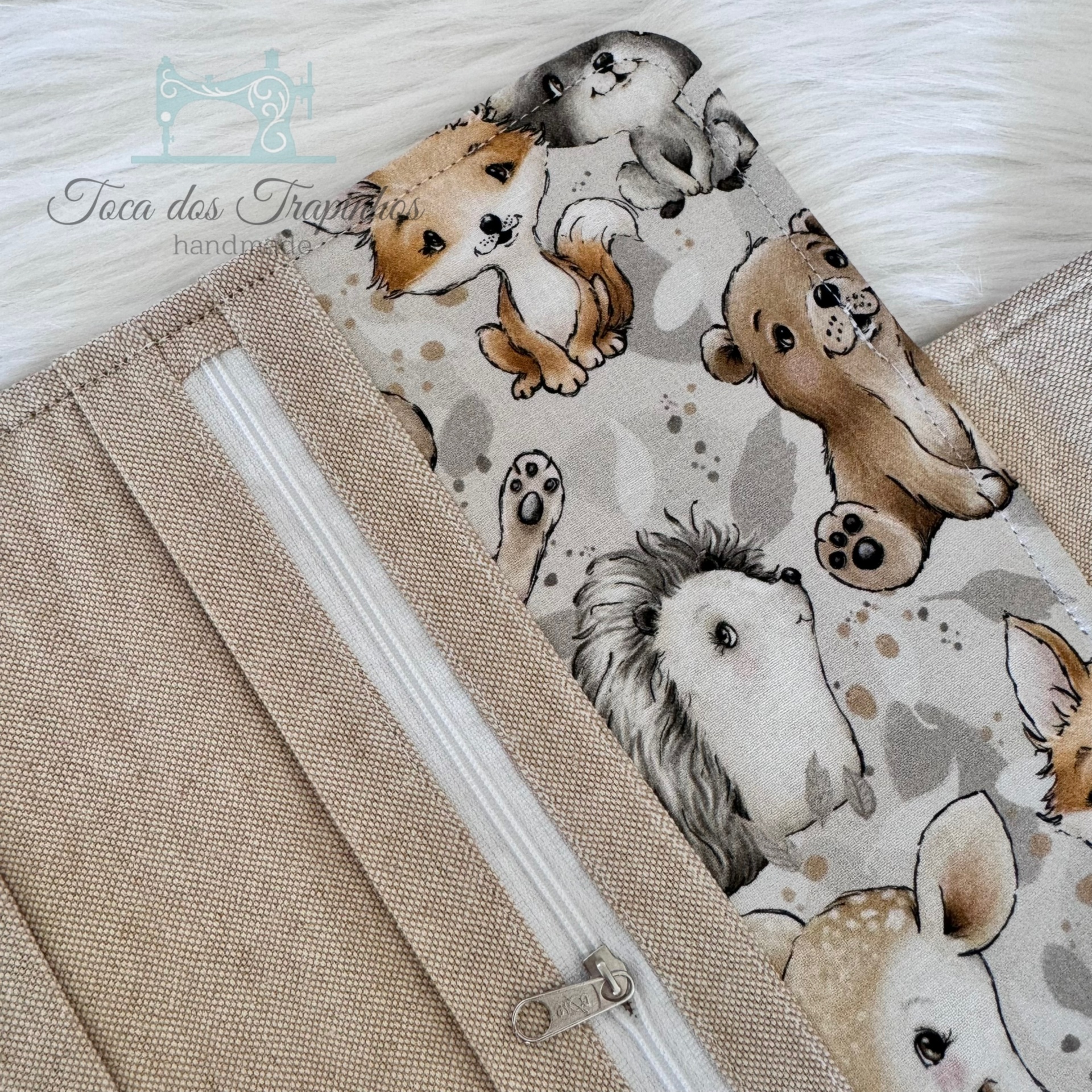 Saco de tecido bege com fecho branco e tecido estampado com animais