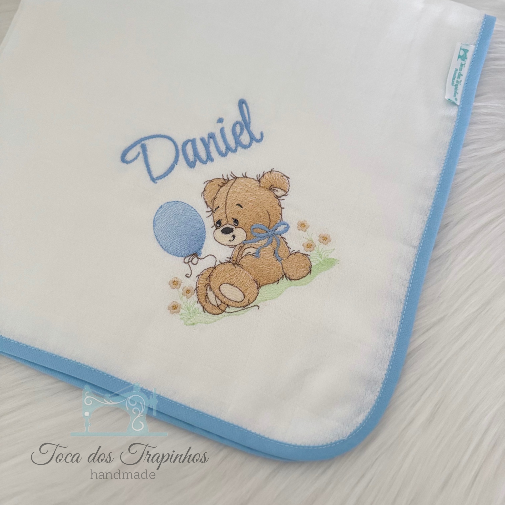 Manta branca com bordado de ursinho e nome Daniel em azul