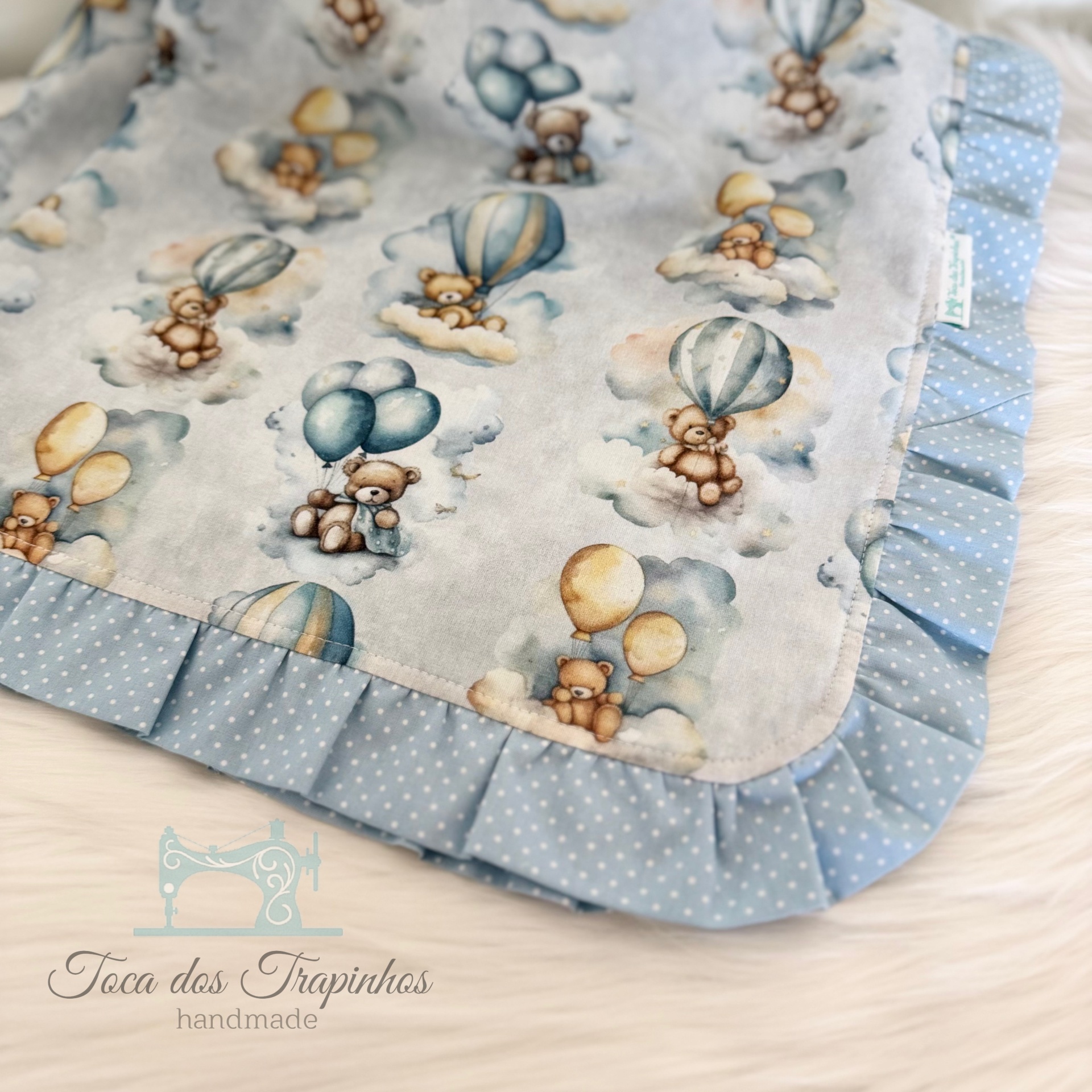 Manta de bebé com padrão de ursos e balões em tecido azul e branco com borda plissada azul claro