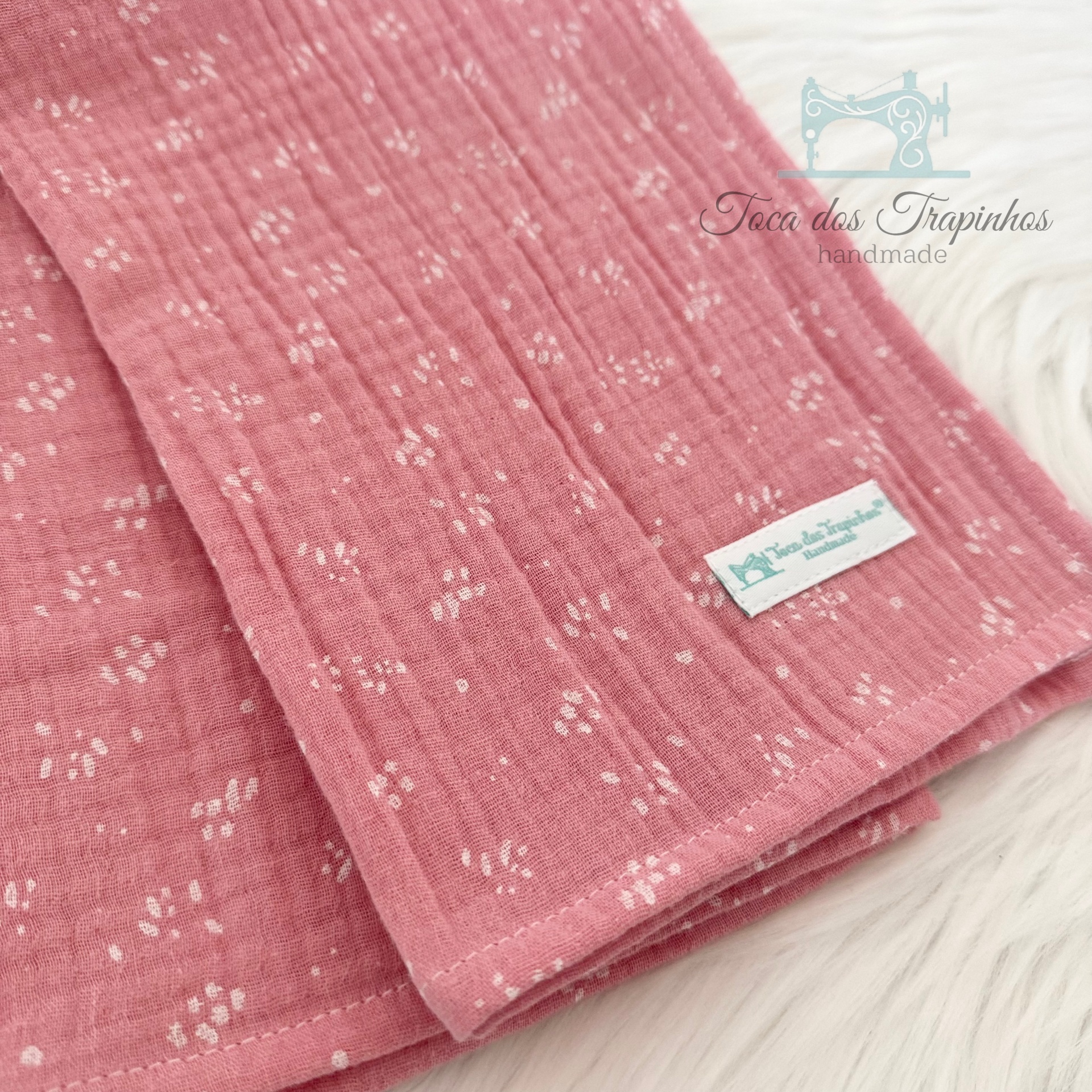 Toalha rosa com padrão floral branco e etiqueta Toca dos Trapinhos handmade