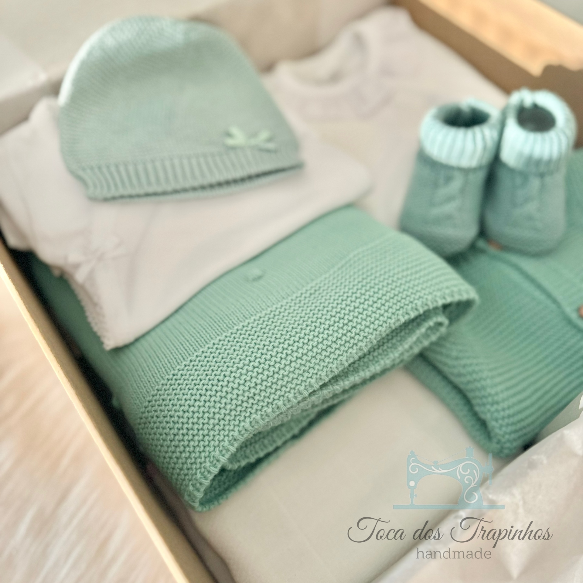 Conjunto de roupa e acessórios de bebé verde menta e branco numa caixa