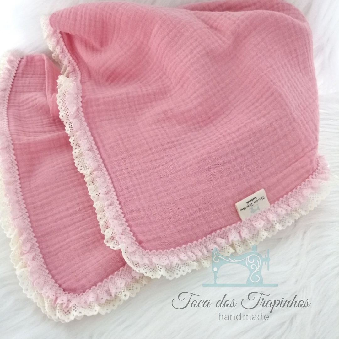 Manta rosa de algodão muselina com borda de renda creme sobre fundo branco