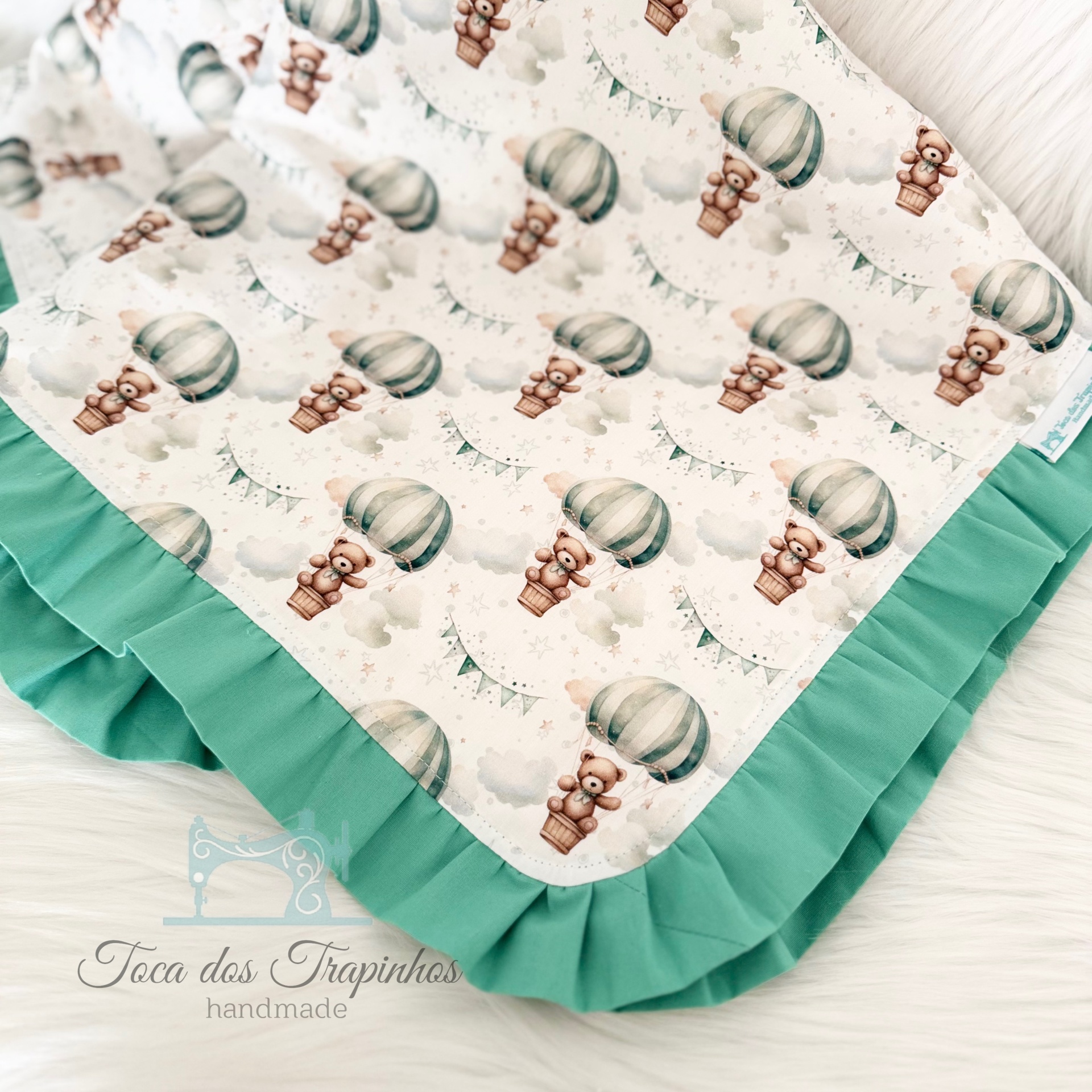 Manta para bebê com padrão de balões e ursos em tecido branco com folho verde