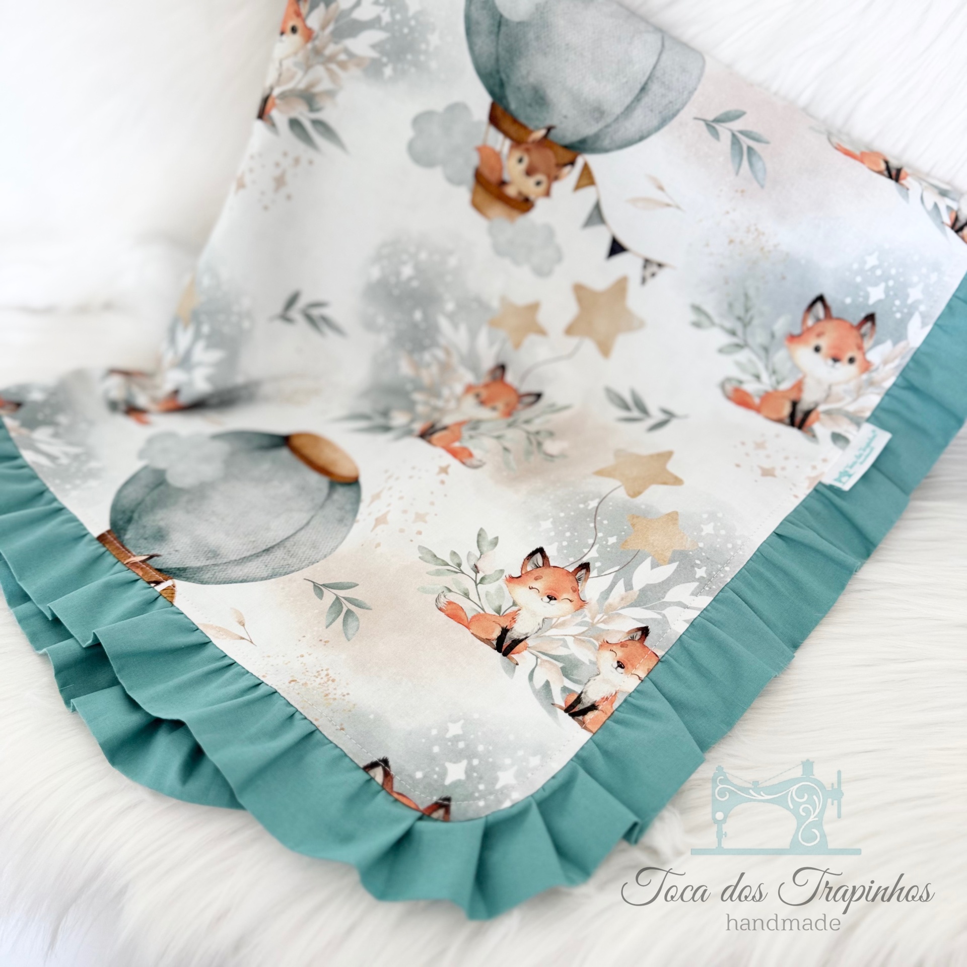 Estendal para bebé com padrão de raposas e balões, friso verde água