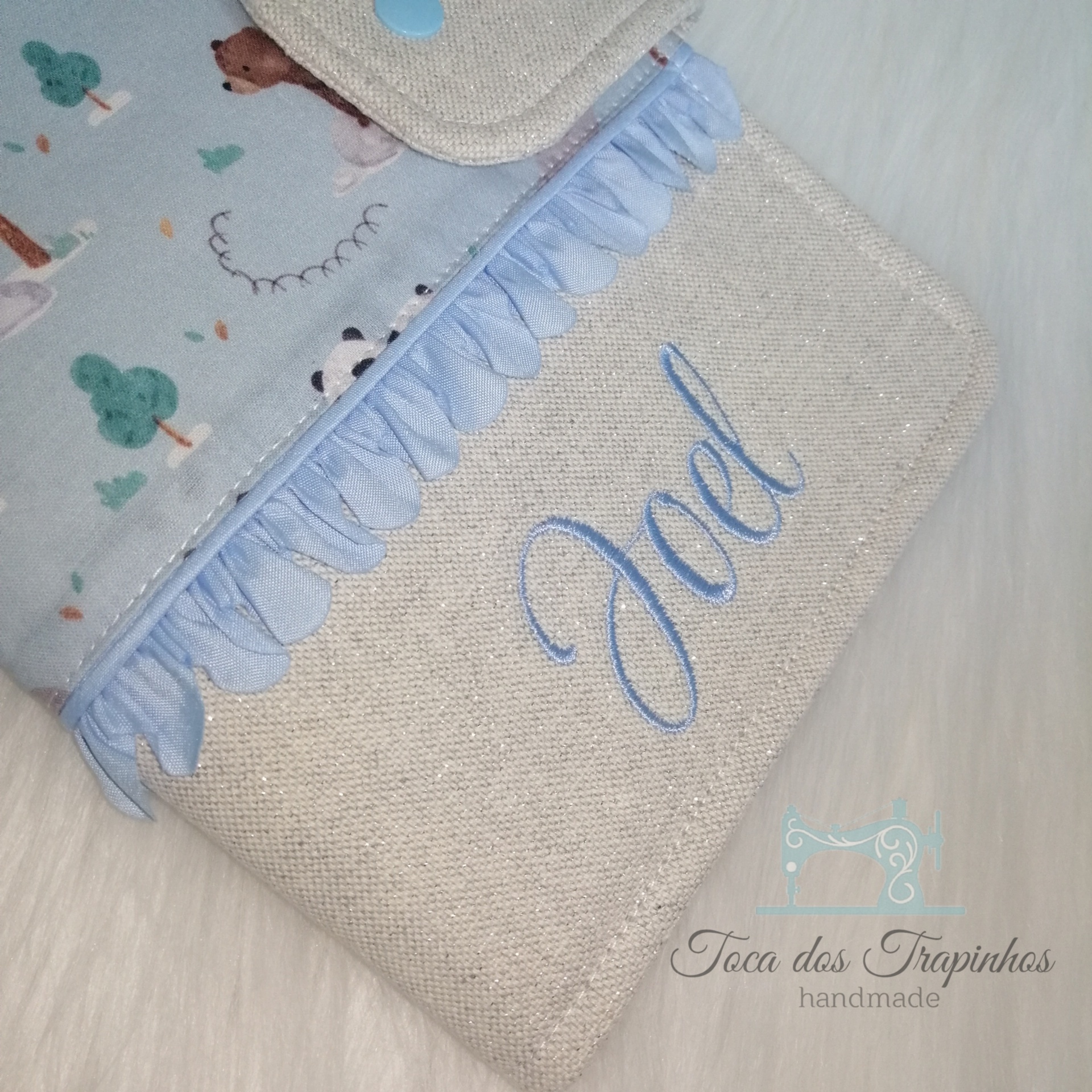 Capa personalizada em tecido bege com bordado azul e estampa infantil azul