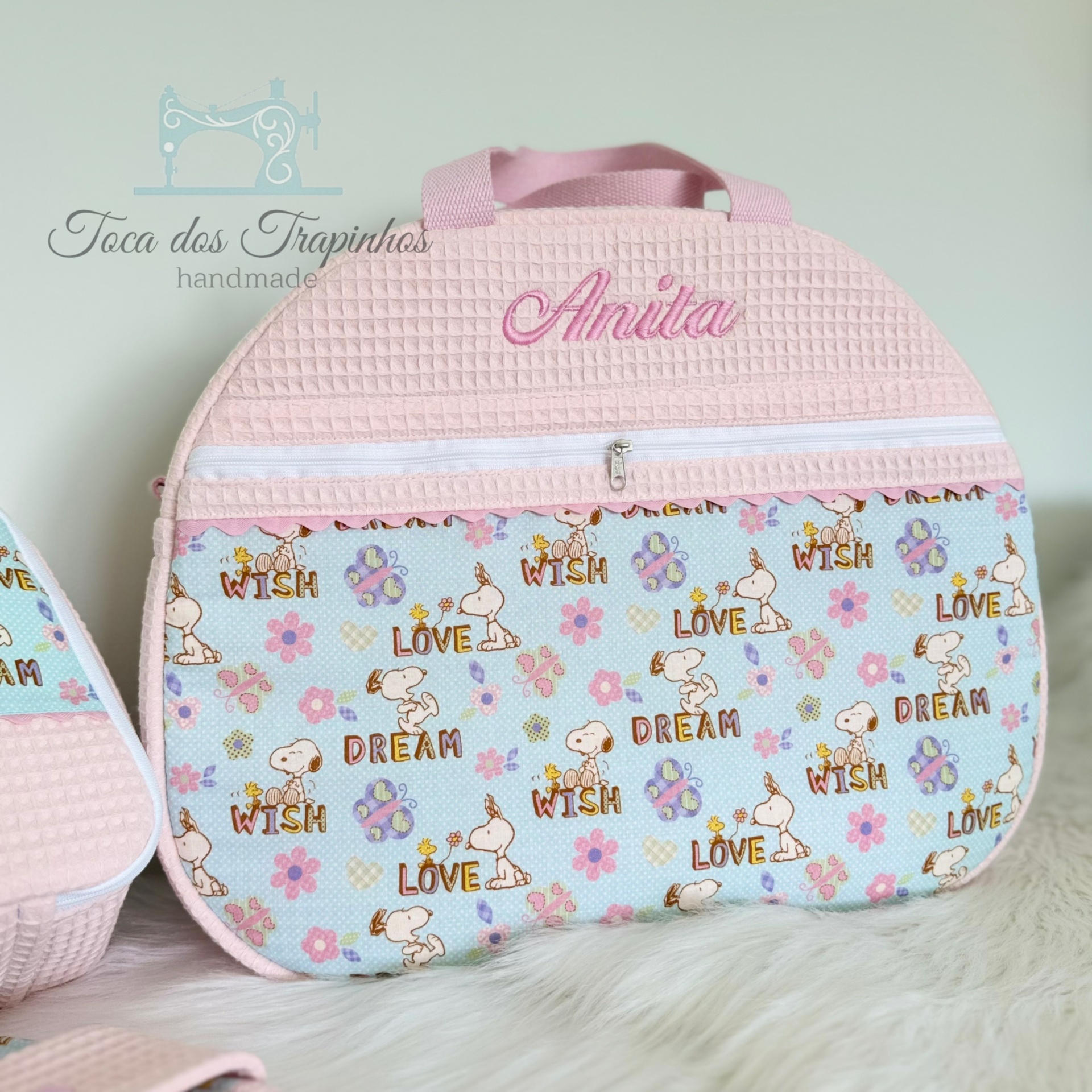 Bolsa infantil decorada com personagens Snoopy e palavras WISH, LOVE, DREAM, nome Anita bordado no rosa texturizado.