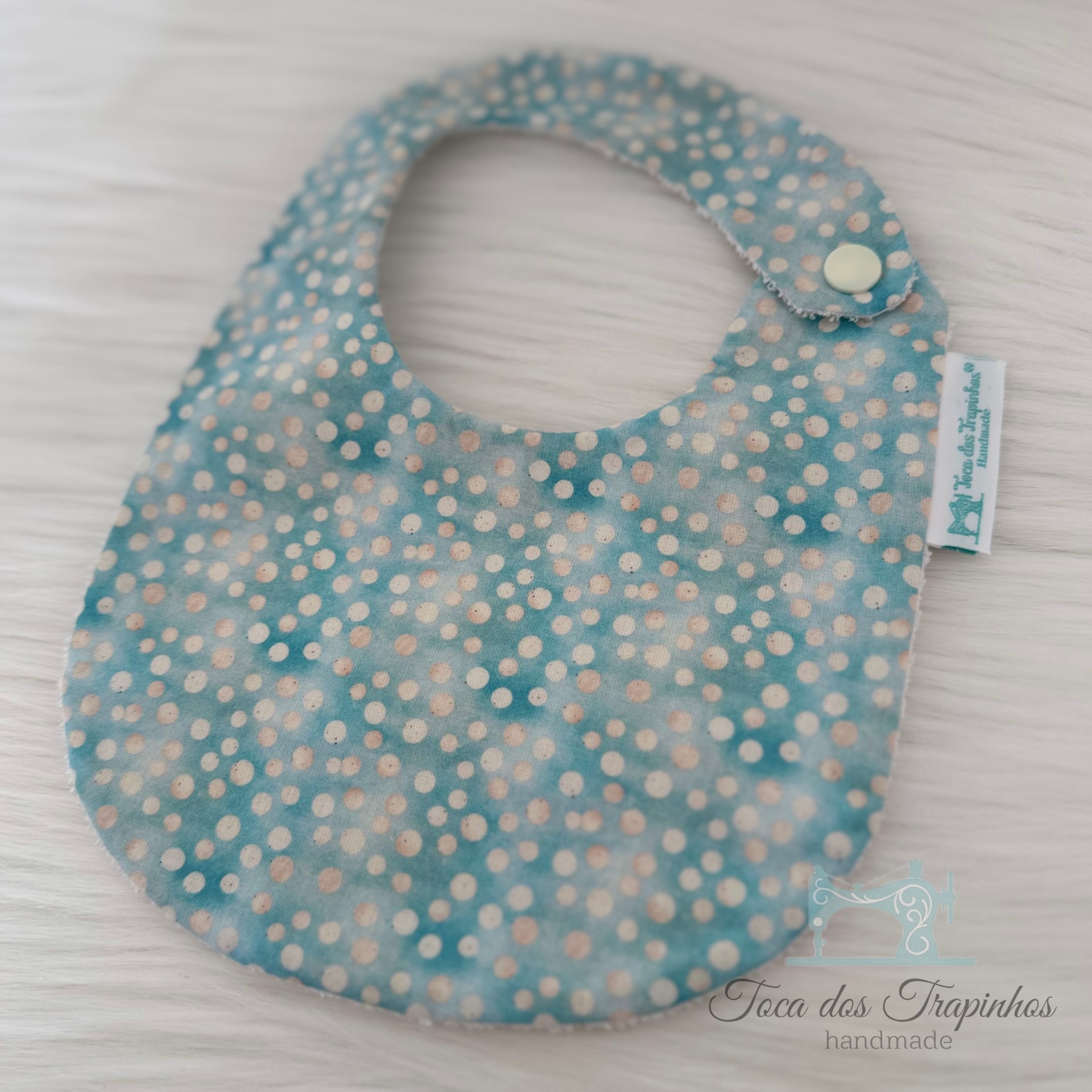 Babete azul com pontos brancos e bege, fecho de pressão e etiqueta Toca dos Trapinhos handmade