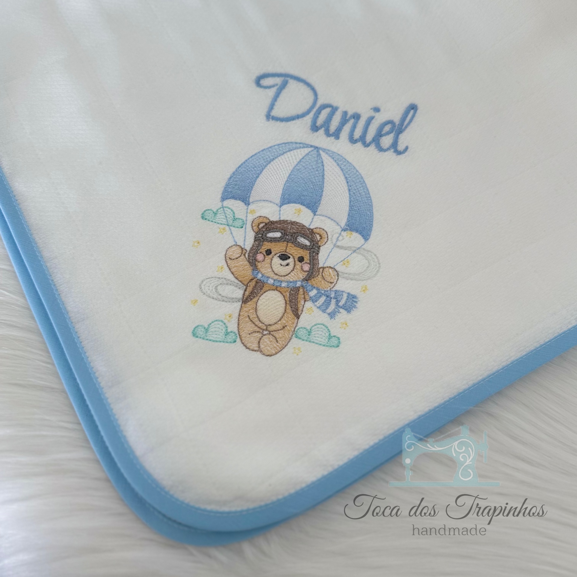 Fralda branca com borda azul e ursinho estampado