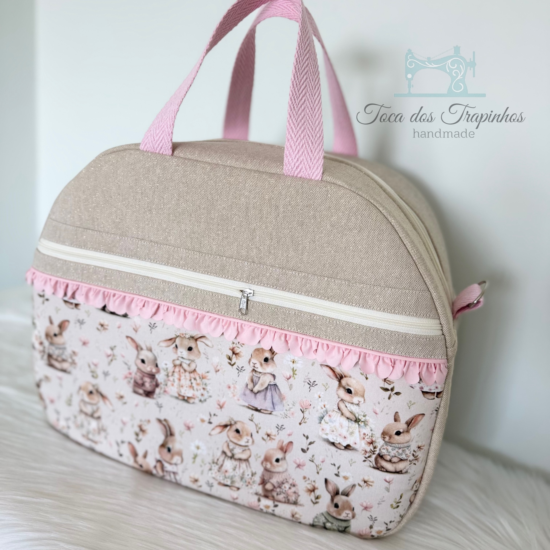 Mala de mão bege e rosa com estampa de coelhos vestidos e ziper branco