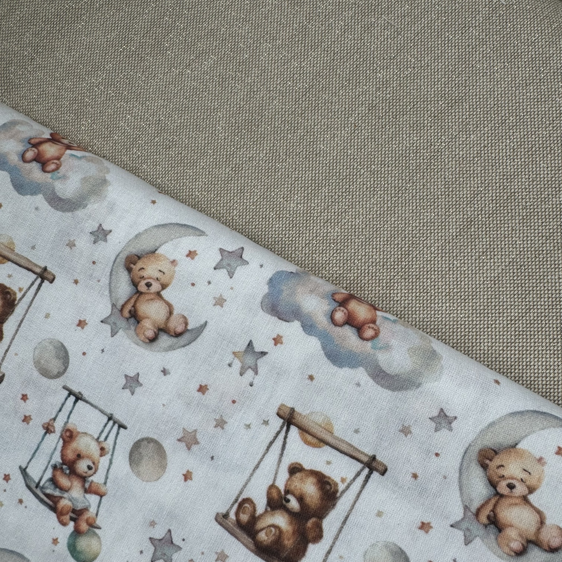 Tecido branco com padrão de ursinhos castanhos e estrelas sobre tecido bege