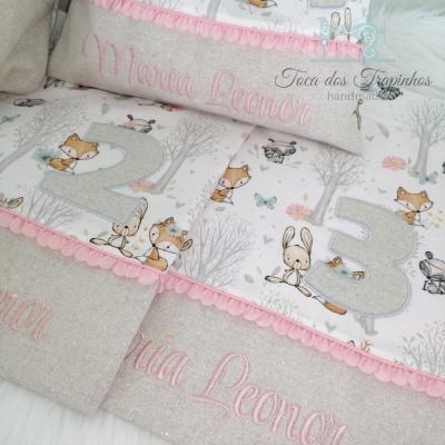 Produtos têxteis para bebé com padrão infantil de animais, números e bordado rosa com nome Maria Leonor.