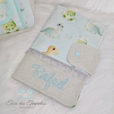 Capa para caderneta de vacinação com estampa de dinossauros e nome Rafael bordado.