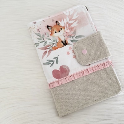 Capa com padrão floral e raposa em tecido bege com botão cor-de-rosa
