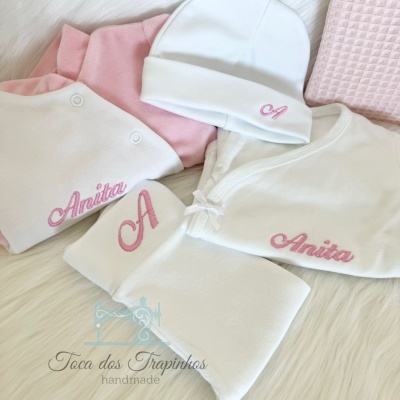 Conjunto de roupa de bebé branca e rosa com bordados em rosa