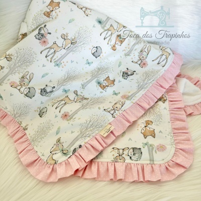 Cobertores infantis com padrão de animais e bordas rosa com pontos brancos.
