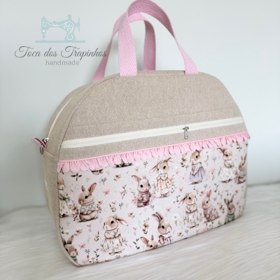 Mala de mão bege com estampa de coelhos e alças rosa