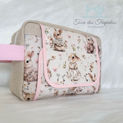 Bolsa pequena retangular com padrão de coelhinhos vestidos e flores, bordas e alça rosa