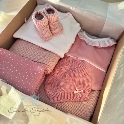 Conjunto de roupa e acessórios de bebê em rosa e branco dentro de caixa de presente