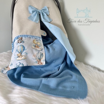 Capa para cadeirinha de bebé bege e azul com motivos de ovelhas e balões e texto artesanal