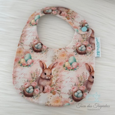 Babete do bebé com padrão de coelhos e ovos em tecido pastel com fecho azul