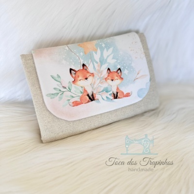Carteira bege com estampa de raposas sobre superfície peluda creme