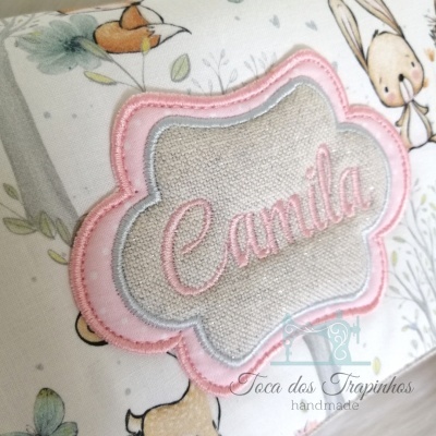 Produto têxtil com bordado do nome Camila e desenhos infantis