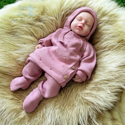 Conjunto de roupa de bebé rosa em malha numa superfície felpuda