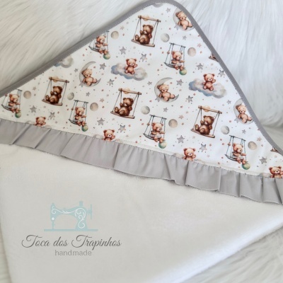 Manta de bebé com padrão de ursinhos e borda cinza.