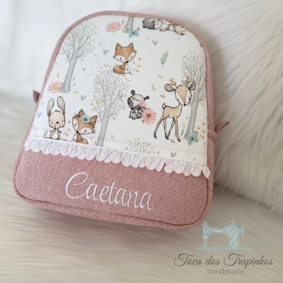 mochila rosa e branca com desenhos de animais e nome bordado em fundo branco