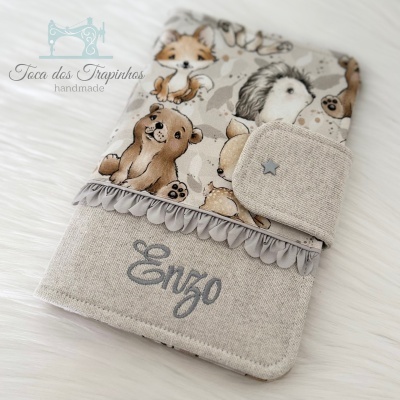 Capa de tecido com estampado de animais e nome 'Enzo' bordado