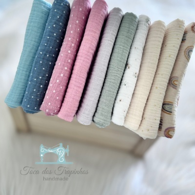 Tecidos dobrados em tons pastel com padrões de bolinhas e arco-íris