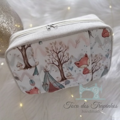 Bolsa branca com padrão de raposas, árvores e tendas, com fecho de correr e etiqueta 'Toca dos Trapinhos handmade'