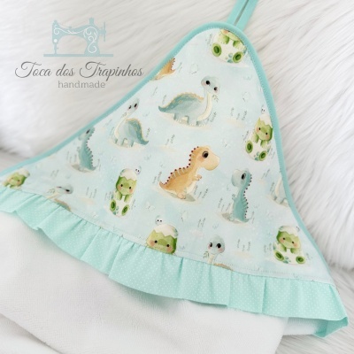 Pano de cozinha com padrão de dinossauros em tecido azul claro com folho