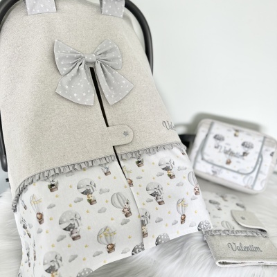 Capa para carrinho de bebé cinza clara com laço e estampa de balões e animais, com bolsa e porta-chupeta à vista