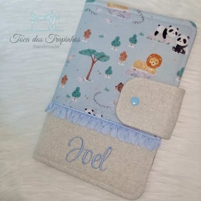 Capa de tecido azul claro com padrão de animais e tecido bege com nome Joel bordado