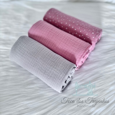 Três panos de algodão rosa e cinza sobre superfície branca com logótipo Toca dos Trapinhos handmade