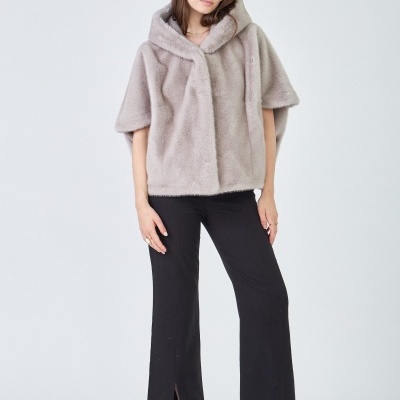 Mulher com casaco de pele cinza claro, calças pretas e sapatos de salto