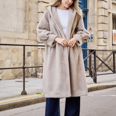 Casaco comprido de pelo sintético cinza claro com capuz, usado por mulher em rua