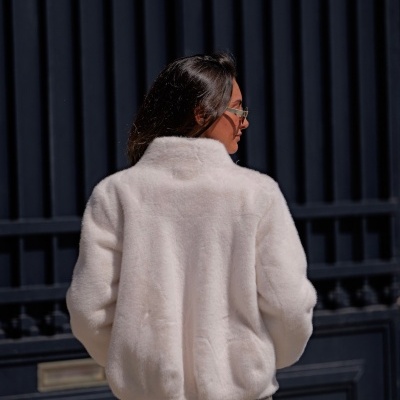 Casaco feminino de pelo branco com gola alta visto de costas na rua
