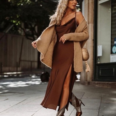 Mulher com vestido castanho e cardigan bege numa rua de cidade