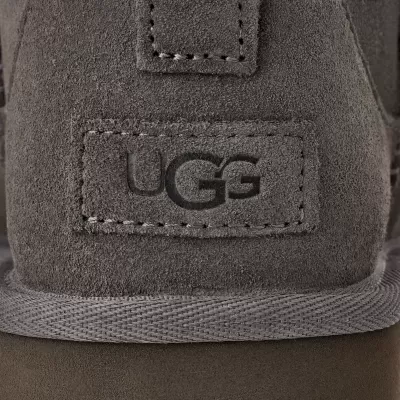 Detalhe do calçado cinzento com etiqueta UGG em relevo