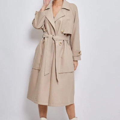 Mulher com casaco trench coat bege e botins bege em fundo branco
