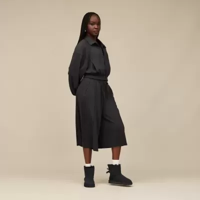 Mulher com casaco e saia pretos com botins pretos