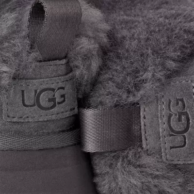 Detalhe de bota cinzenta de camurça com pelo e tiras de tecido, logo UGG