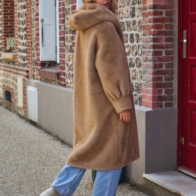 Casaco comprido bege felpudo com capuz e punhos elásticos numa rua de pedra