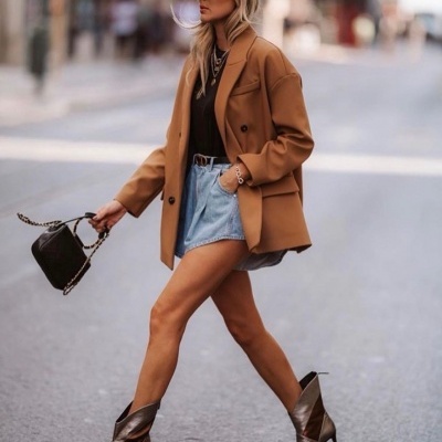 Mulher com blazer castanho, calções de ganga e botas de salto
