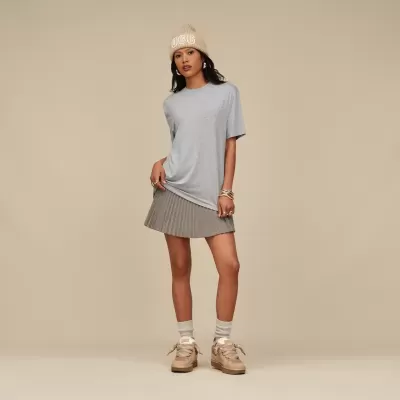 Mulher com roupa casual cinzenta e bege com gorro UGG em fundo bege.