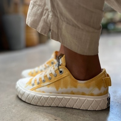 Ténis amarelos tie-dye com sola branca e atacadores brancos