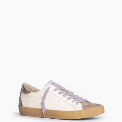 Ténis de couro branco com detalhe em camurça e padrão atrás