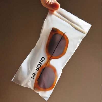 Estojo branco com óculos de sol amarelo-âmbar visíveis através da embalagem, texto MR. BOHO